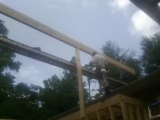 Carpenter setting a ridge beam over a new addition frame — Ice Dam Removal by Roofing Brothers in Deatsville