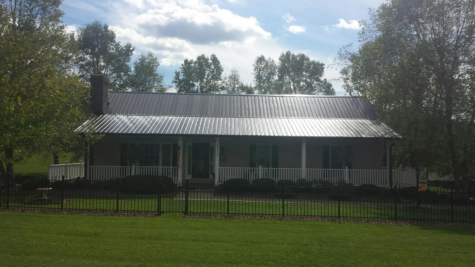 Gray metal roof on a brick ranch with a full width front porch — Gutter Guard Installation work by our crew in Deatsville