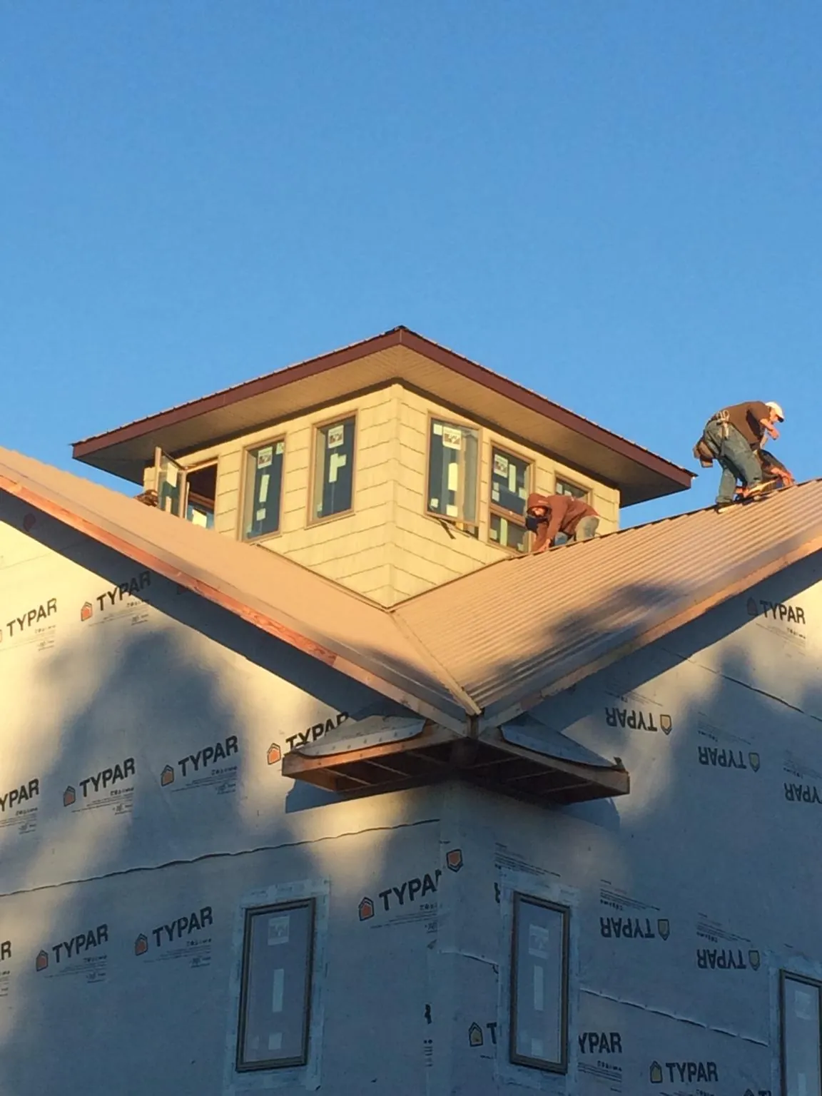 Roofers working around a rooftop cupola on a new metal roof at sunset — Roof Waterproofing in Deatsville by Roofing Brothers